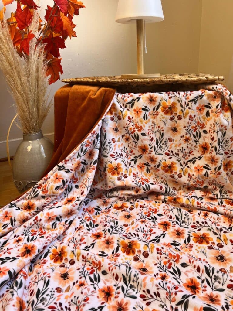 Plaid d’automne fleuri 150 x 200 cm cousu main, avec verso jaune moutarde. Un plaid XXL doux et chaleureux, en stock et expédié sous 8 jours.